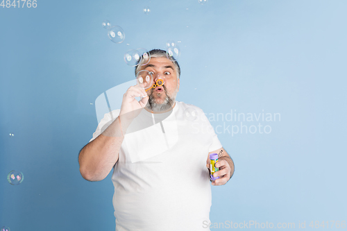 Image of Handsome caucasian plus size male model isolated on blue studio background. Concept of inclusion, human emotions, facial expression