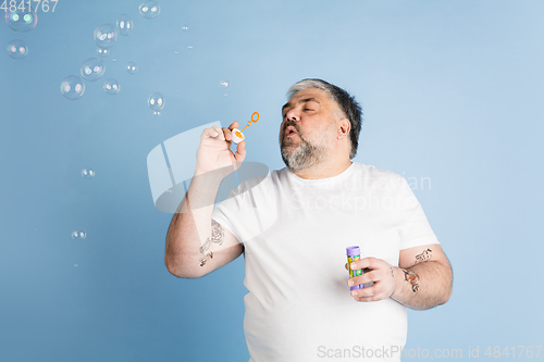 Image of Handsome caucasian plus size male model isolated on blue studio background. Concept of inclusion, human emotions, facial expression