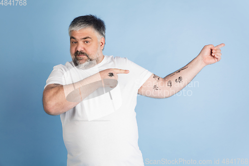 Image of Handsome caucasian plus size male model isolated on blue studio background. Concept of inclusion, human emotions, facial expression