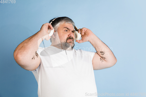 Image of Handsome caucasian plus size male model isolated on blue studio background. Concept of inclusion, human emotions, facial expression