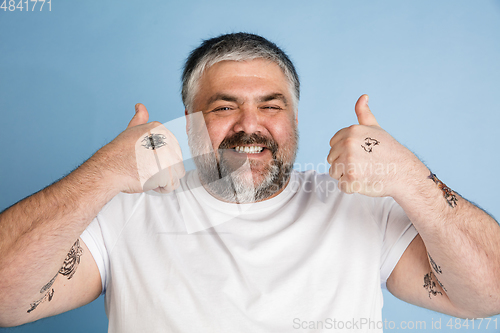 Image of Handsome caucasian plus size male model isolated on blue studio background. Concept of inclusion, human emotions, facial expression