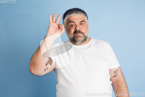 Image of Handsome caucasian plus size male model isolated on blue studio background. Concept of inclusion, human emotions, facial expression