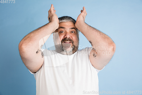 Image of Handsome caucasian plus size male model isolated on blue studio background. Concept of inclusion, human emotions, facial expression