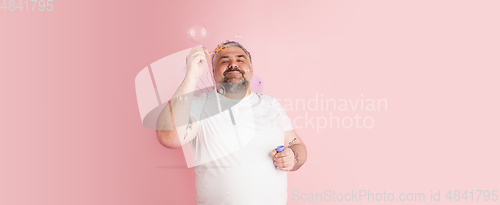 Image of Handsome caucasian plus size male model isolated on coral pink studio background. Concept of inclusion, human emotions, facial expression