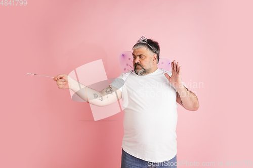 Image of Handsome caucasian plus size male model isolated on coral pink studio background. Concept of inclusion, human emotions, facial expression