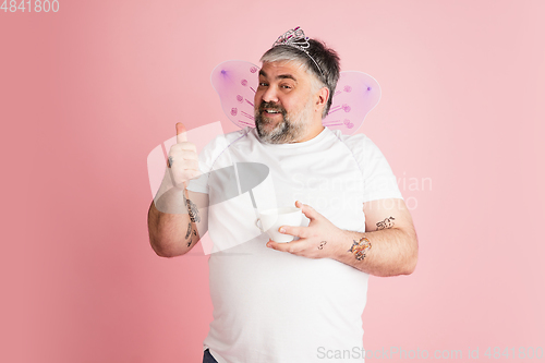 Image of Handsome caucasian plus size male model isolated on coral pink studio background. Concept of inclusion, human emotions, facial expression