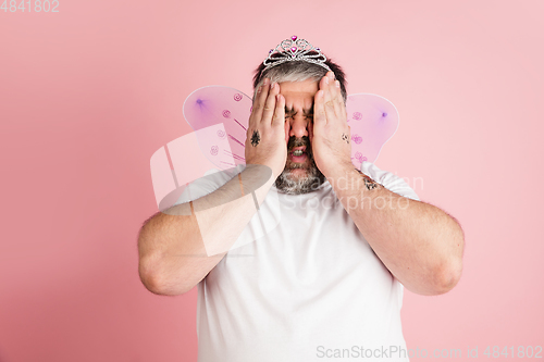 Image of Handsome caucasian plus size male model isolated on coral pink studio background. Concept of inclusion, human emotions, facial expression