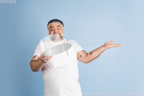 Image of Handsome caucasian plus size male model isolated on blue studio background. Concept of inclusion, human emotions, facial expression