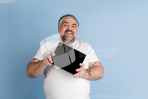 Image of Handsome caucasian plus size male model isolated on blue studio background. Concept of inclusion, human emotions, facial expression