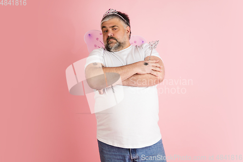 Image of Handsome caucasian plus size male model isolated on coral pink studio background. Concept of inclusion, human emotions, facial expression