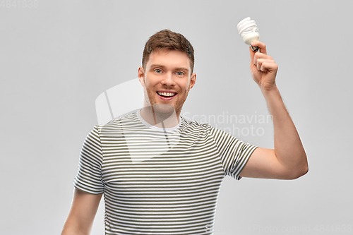 Image of smiling young man holding lighting bulb