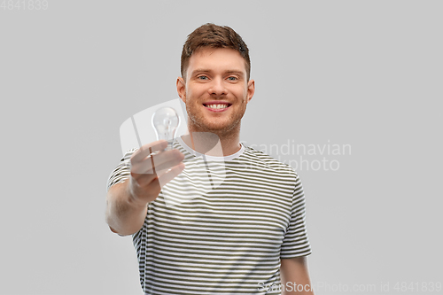 Image of happy smiling young man holding light bulb