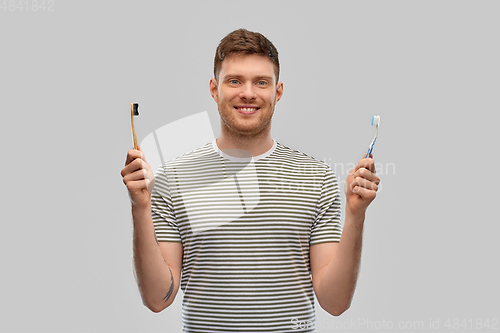 Image of man comparing wooden and plastic toothbrush