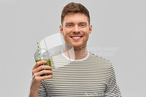 Image of man drinking green smoothie from disposable cup