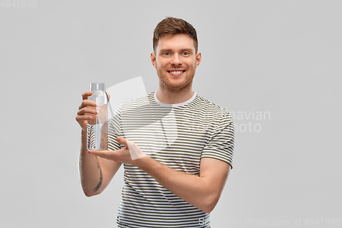 Image of happy smiling man holding water in glass bottle
