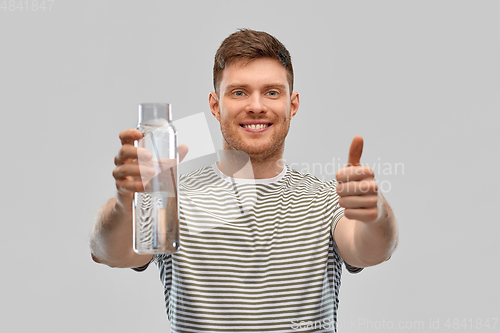 Image of happy smiling man holding water in glass bottle