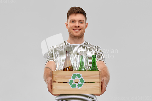 Image of smiling young man sorting glass waste