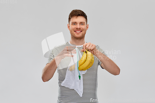 Image of smiling man putting bananas into reusable net bag