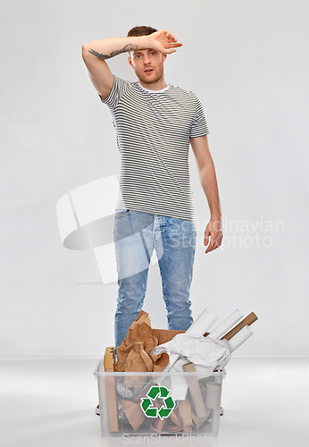 Image of tired young man sorting paper waste