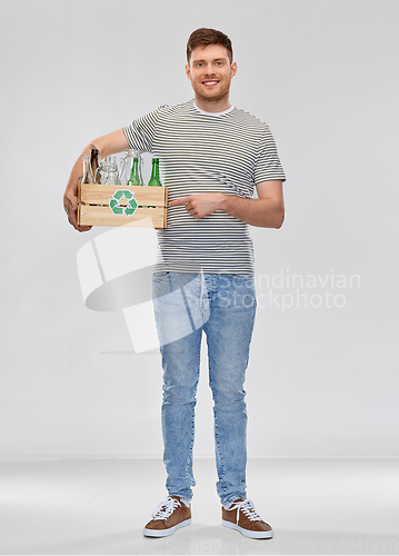 Image of smiling young man sorting glass waste