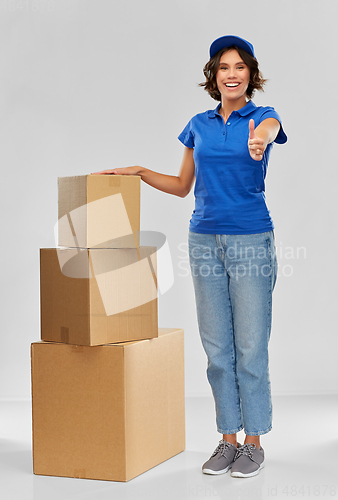 Image of happy delivery girl with parcel boxes in blue