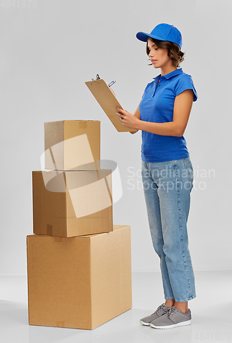 Image of happy delivery girl with boxes and clipboard