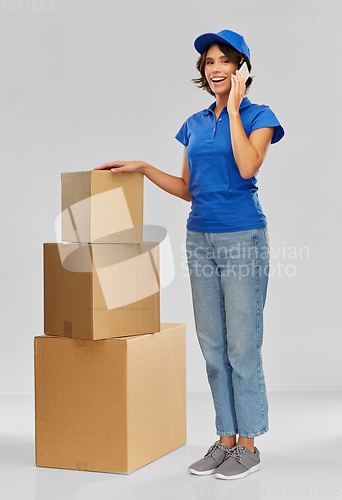 Image of delivery woman with boxes calling on smartphone