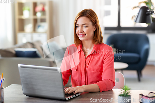 Image of happy woman with laptop working at home office