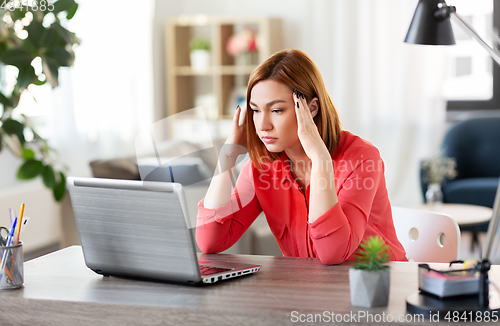 Image of stressed woman with laptop working at home office