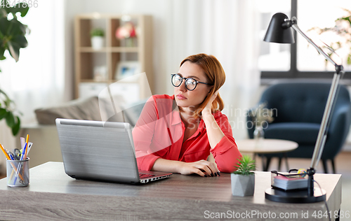 Image of bored woman with laptop working at home office