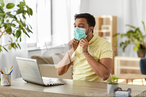 Image of indian man in mask with laptop at home office