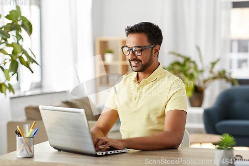 Image of indian man with laptop working at home office