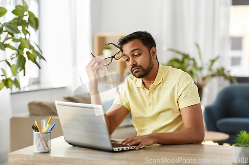 Image of bored man with laptop working at home office