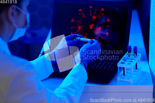 Image of hand holding beaker with coronavirus blood test