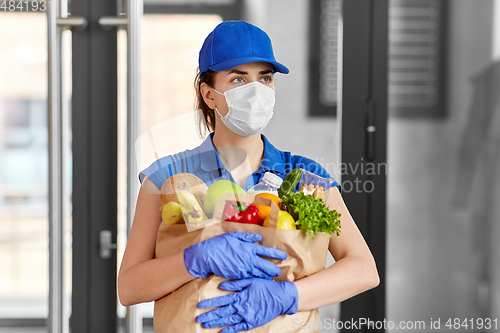 Image of delivery woman in face mask with food in paper bag