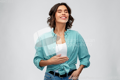 Image of happy full young woman touching her tummy