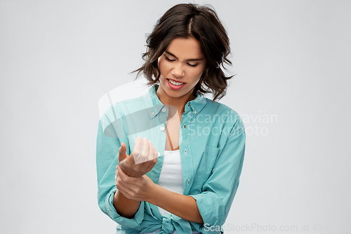 Image of young woman in shirt suffering from pain in hand