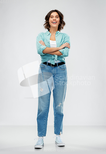 Image of smiling young woman in turquoise shirt and jeans