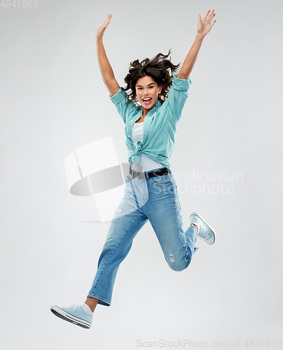 Image of happy young woman jumping over grey background