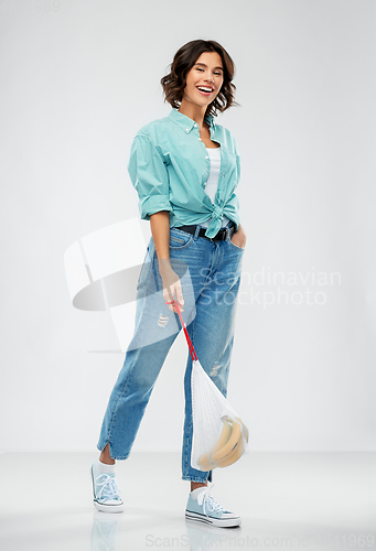 Image of happy woman with bananas in reusable string bag