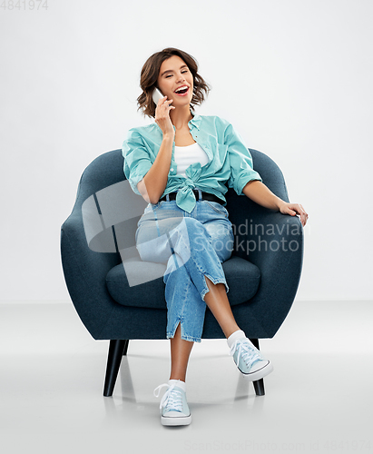 Image of woman sitting in chair and calling on smartphone