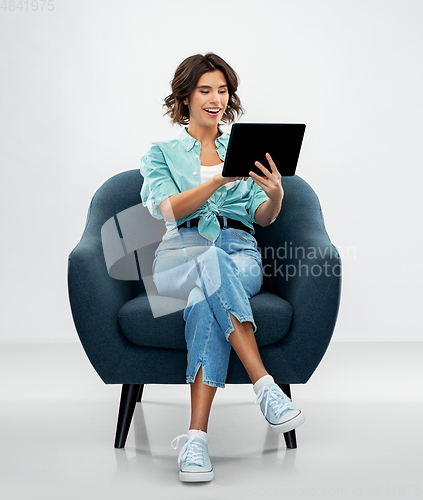 Image of happy woman with tablet pc sitting in armchair