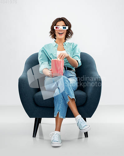 Image of woman in 3d movie glasses eating popcorn in chair