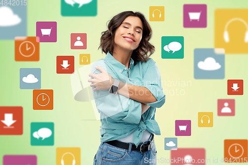 Image of smiling woman with smart watch hugging herself