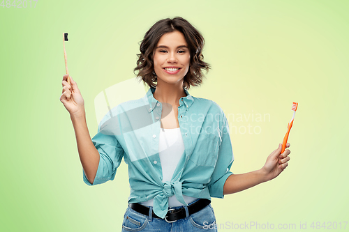 Image of woman comparing wooden and plastic toothbrush