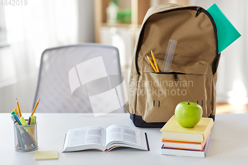 Image of books, apple and school supplies on table at home