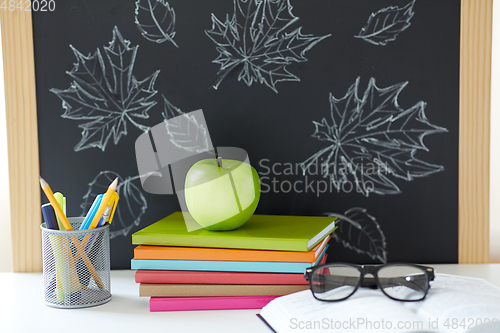 Image of books, apple and school supplies on table at home