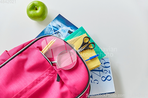 Image of backpack with books, school supplies and apple