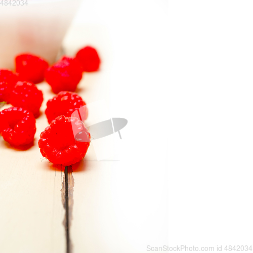 Image of bunch of fresh raspberry on a bowl and white table