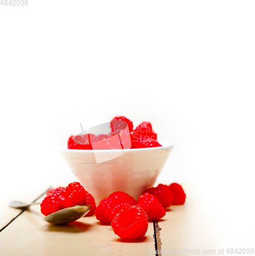 Image of bunch of fresh raspberry on a bowl and white table